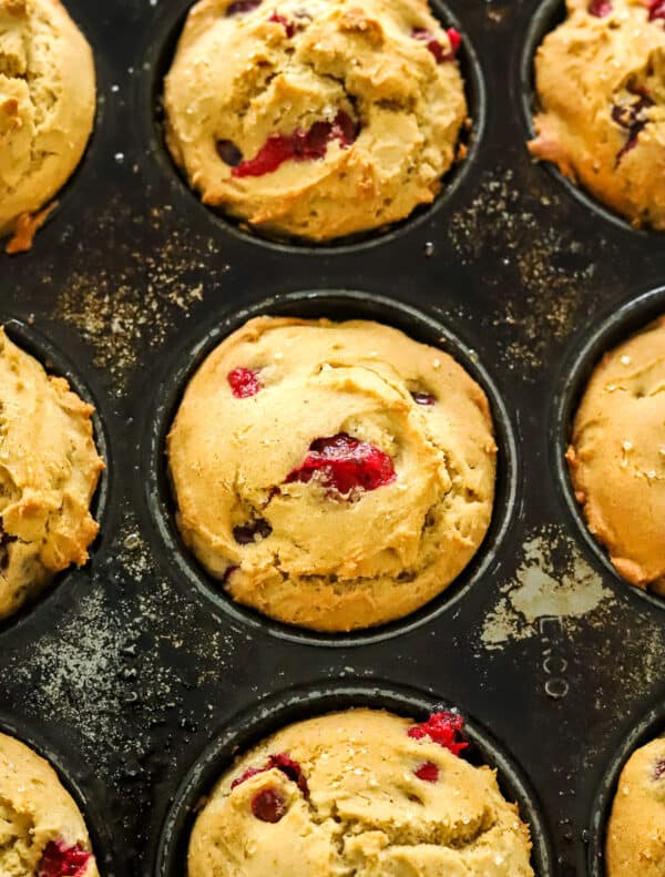 Close up of cranberry muffins in a dark muffin pan.
