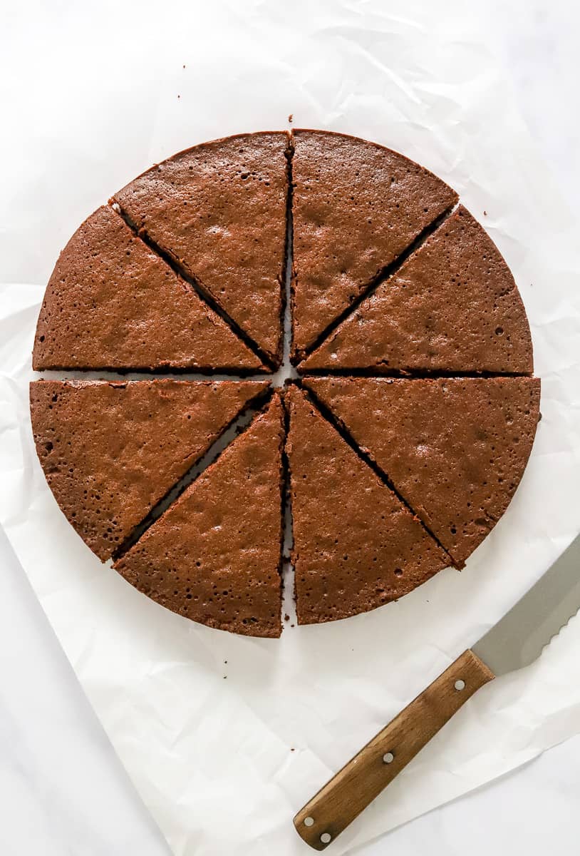 Baked brownies cut into triangles with a knife in front of them. 