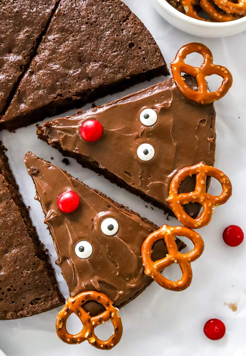 2 frosted and decorated reindeer brownies  with more undecorated brownies next to them. 