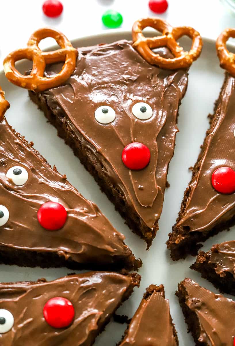 Close up of triangle frosted brownies decorated like Christmas reindeer with pretzels for the antlers. 
