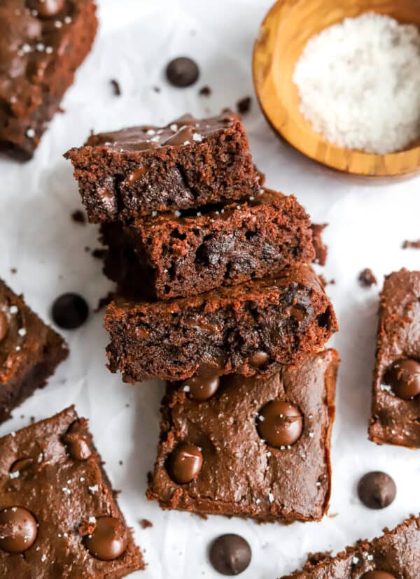 3 fudgy brownies in a row with the cut side of them showing with more brownies around them.
