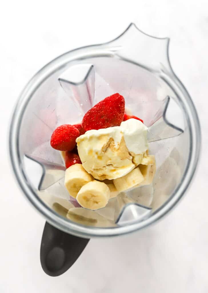 Frozen strawberries, bananas, and yogurt in a blender.