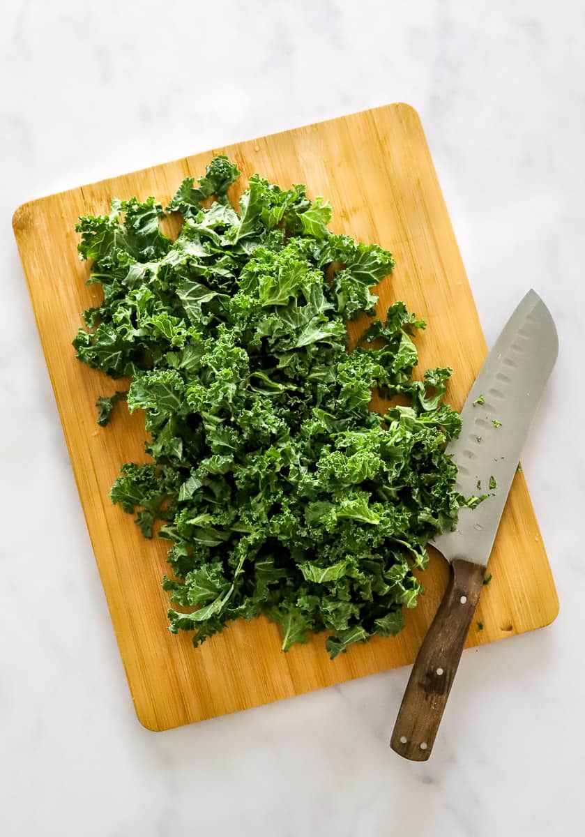Chopped kale on a cutting board with a knife on the board next to it.