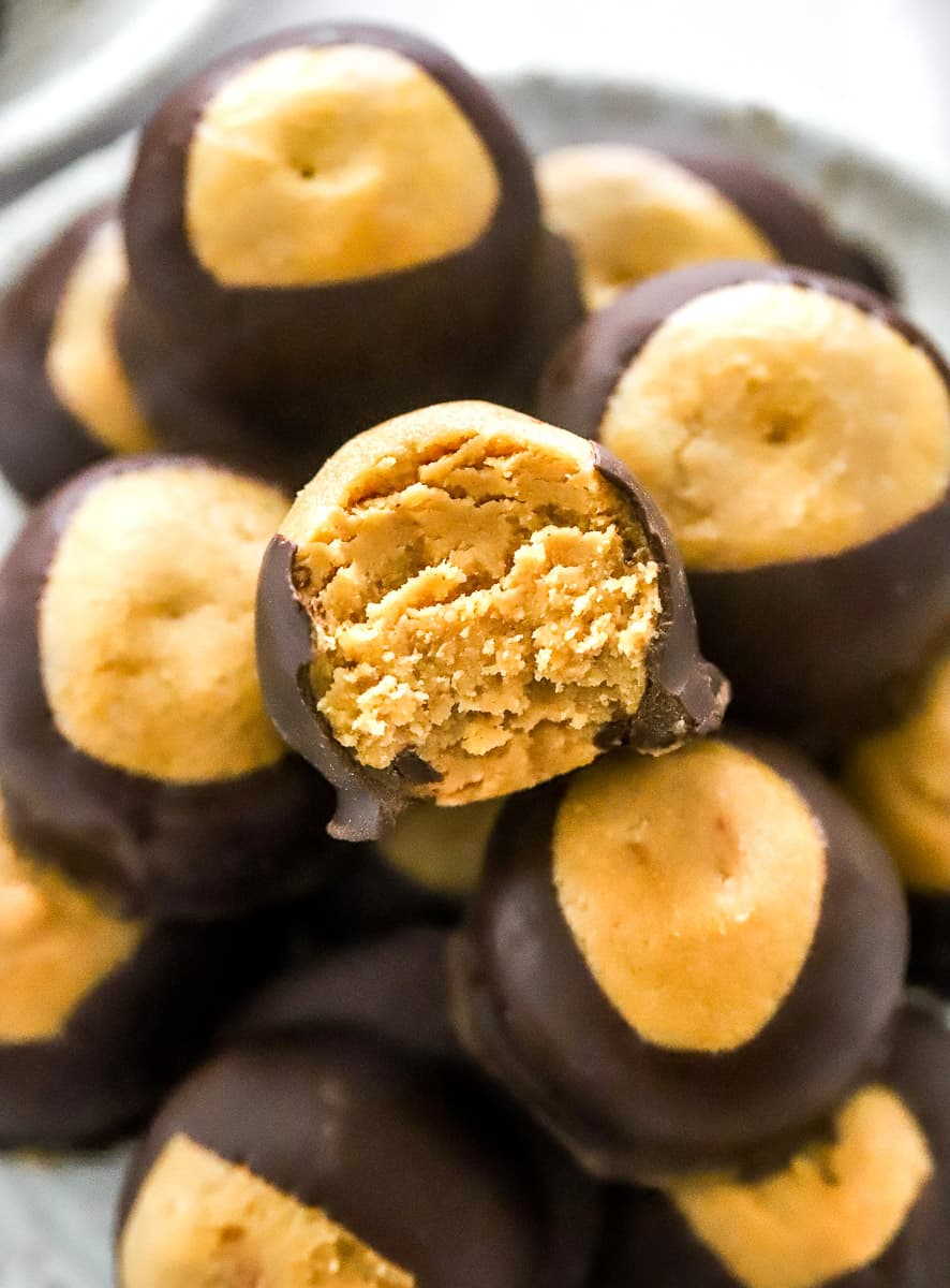 Peanut butter chocolate buckeyes close ups shot with a bite taken out of one. 