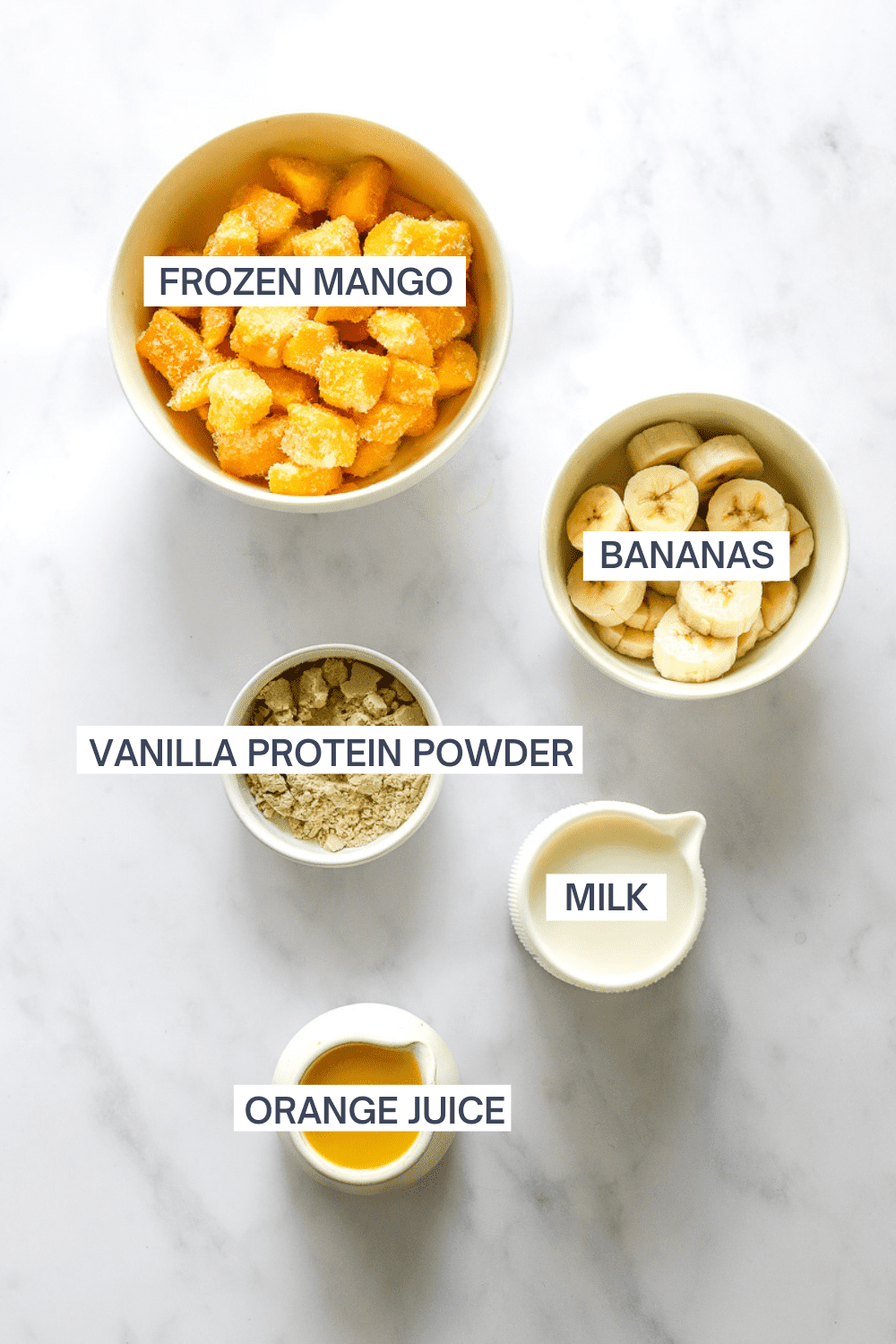Mango banana smoothie ingredients in bowls with labels over each ingredient. 