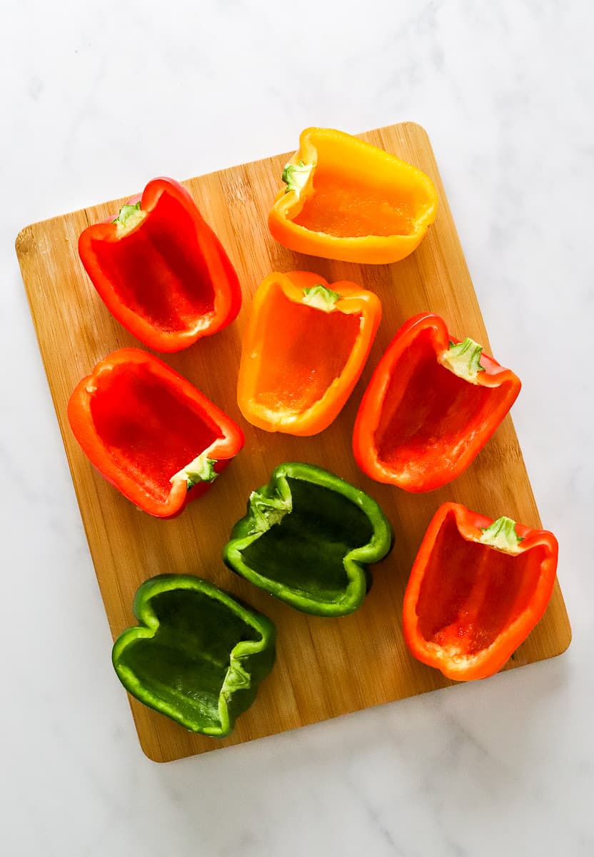 Sliced collared bell peppers on a light brown cutting board.