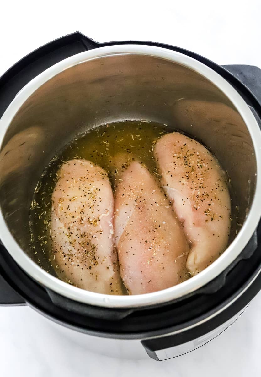 3 raw boneless chicken breasts with no skin, in seasoned water in an instant pot.