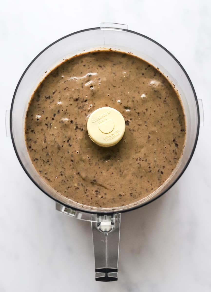Blended eggs, avocado and chocolate in the bowl of a food processor.