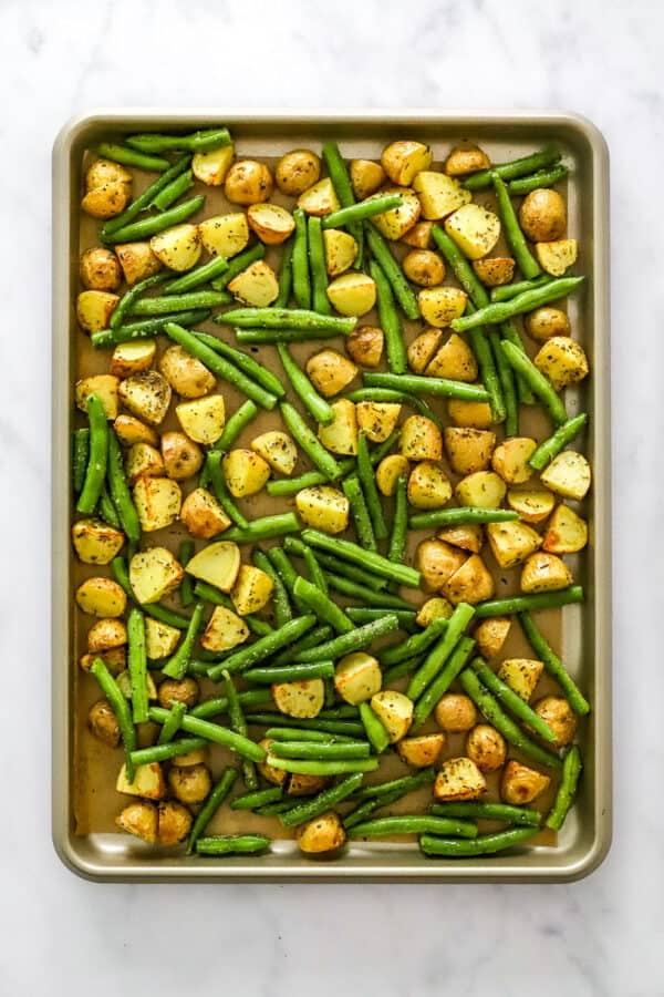 Sheet pan filled with cooked potatoes and green beans.