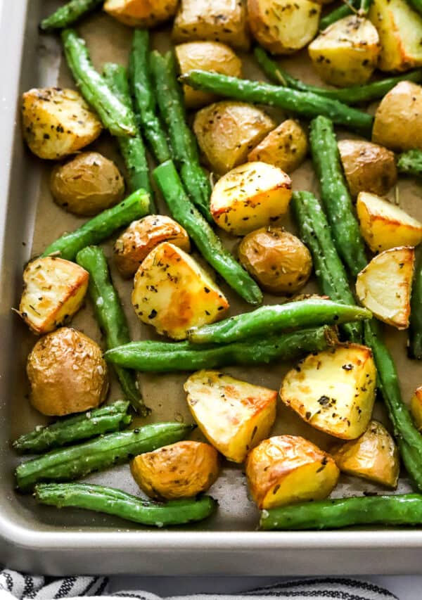 Close up of cooked green beans with potatoes on a baking pan.