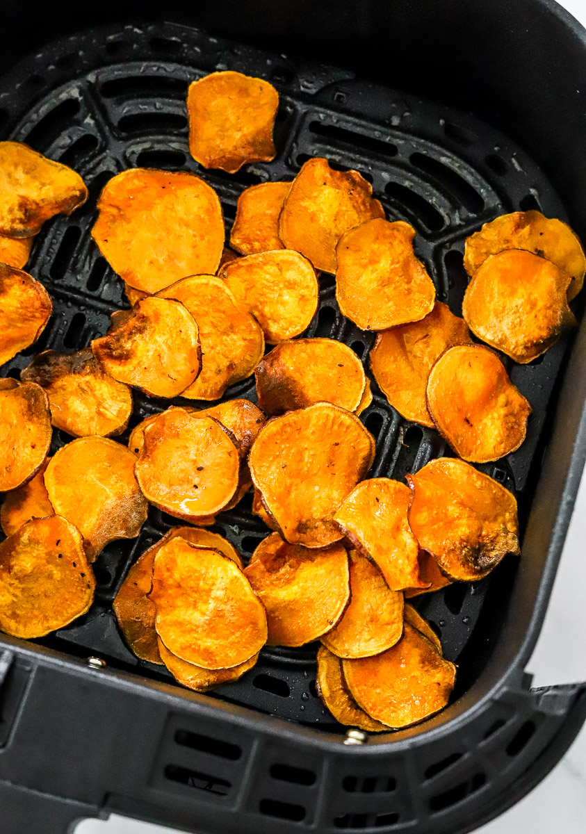 Crispy sweet potato chips in a black air fryer basket. 