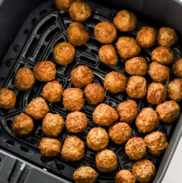 Cooked turkey meatballs in a black air fryer basket.