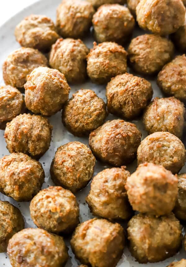 Close up of cooked meatballs on a white plate.