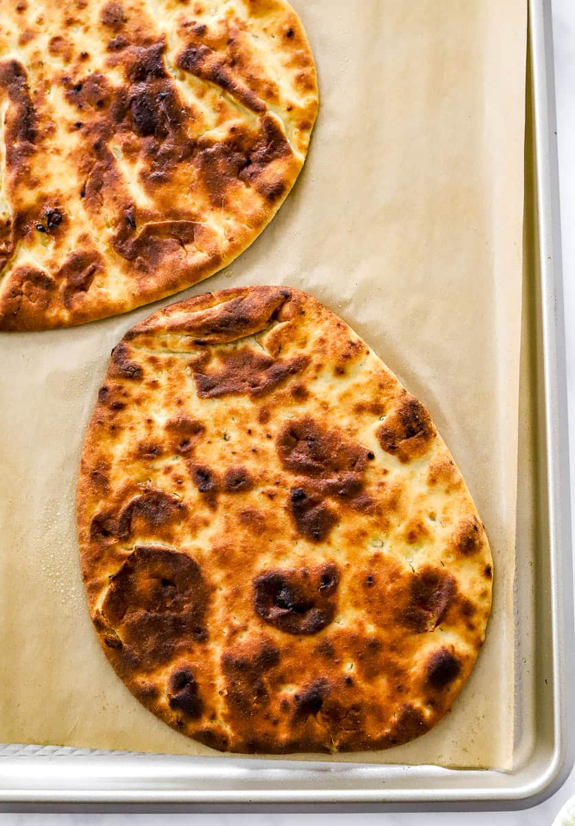 Golden brown round flatbread on a lined baking pan.