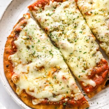 Golden cooked naan pizza topped with red sauce and cheese cut into large, rectangular pieces.