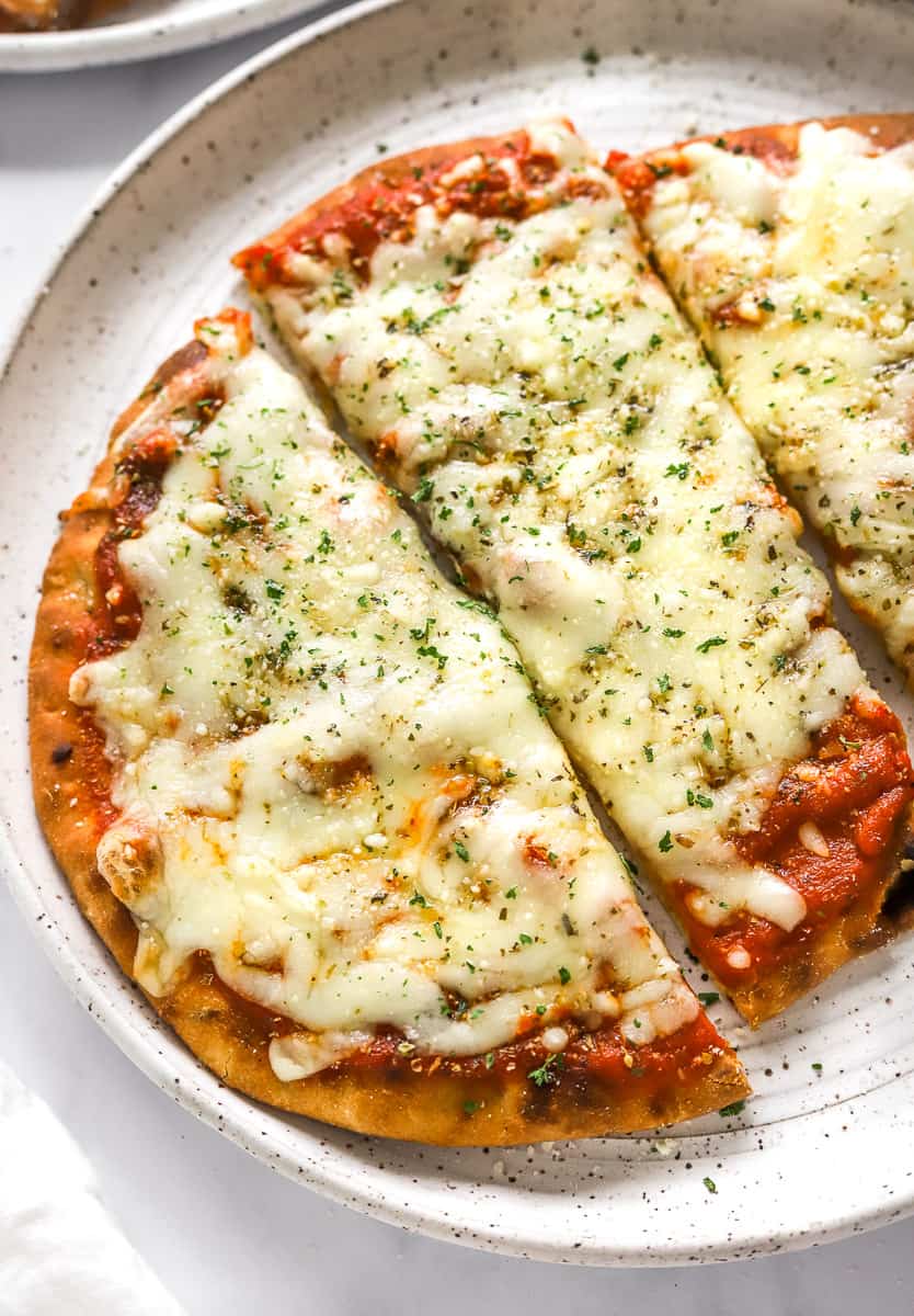 Golden cooked round flatbread topped with red sauce and cheese cut into large, rectangular pieces.