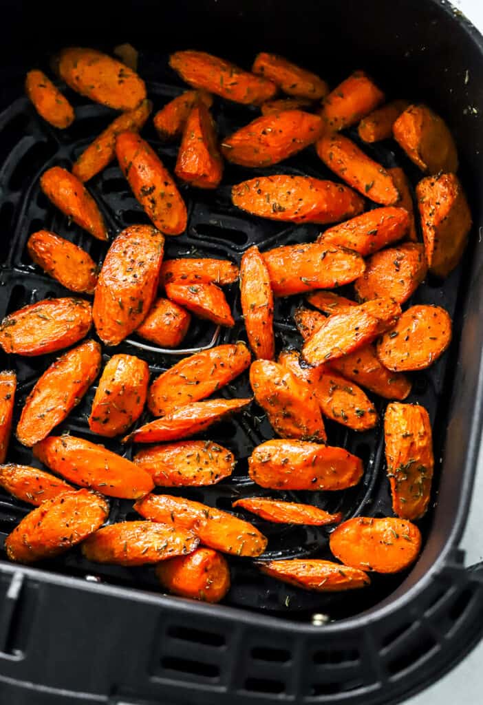 Roasted cooked carrots in an air fryer basket. 