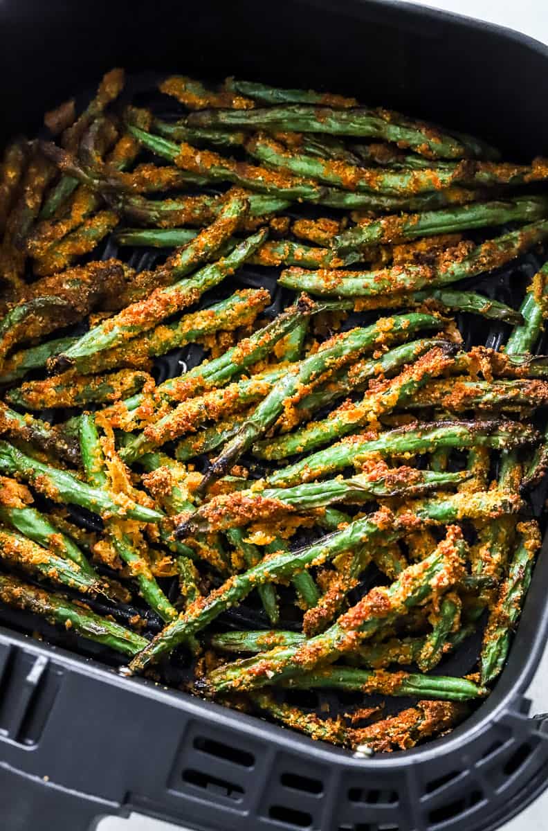 Close up of crispy coated green beans in an air fryer.