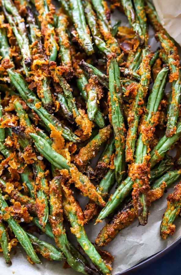 Cooked green bean fries on brown parchment paper.