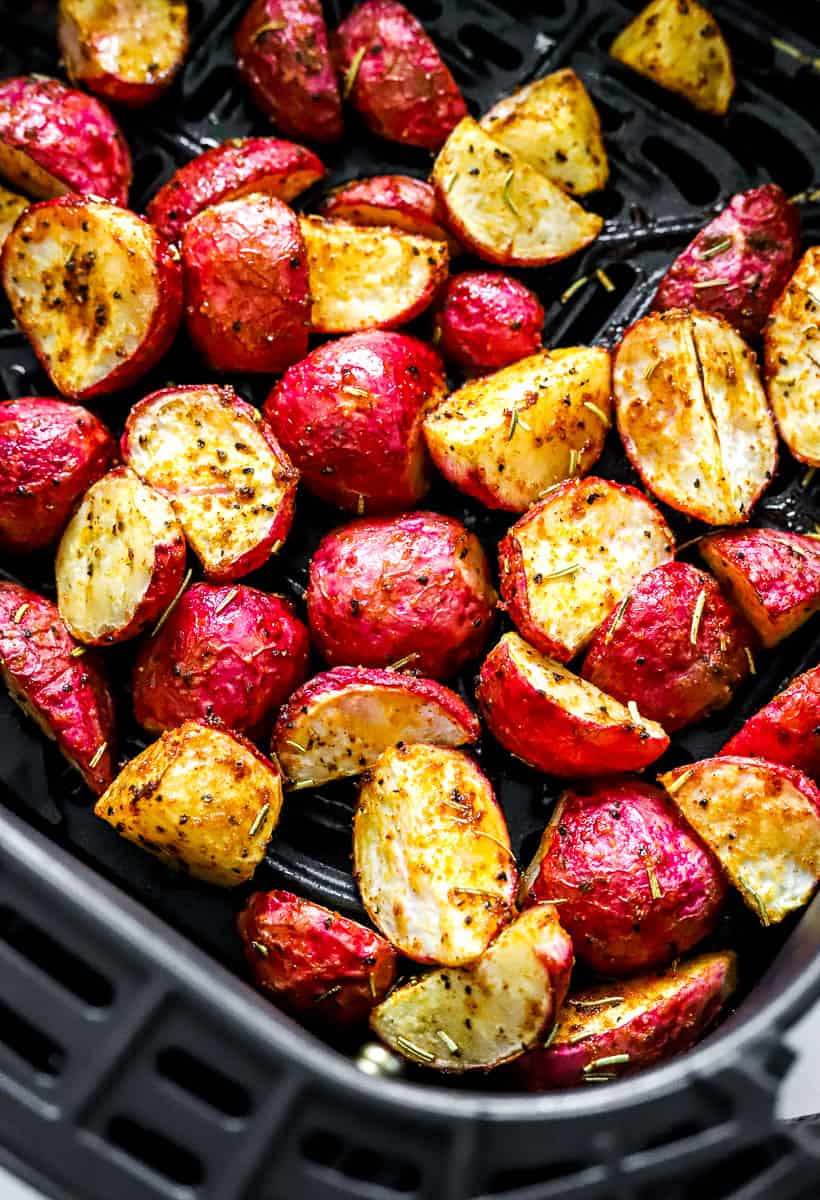 Crispy cooked radishes covered in seasoning in an air fryer basket. 