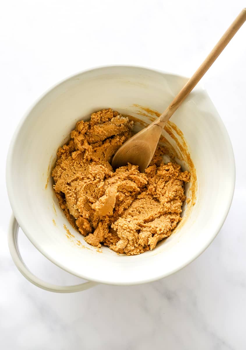 Peanut butter filling in a white mixing bowl with a wooden spoon in the bowl.