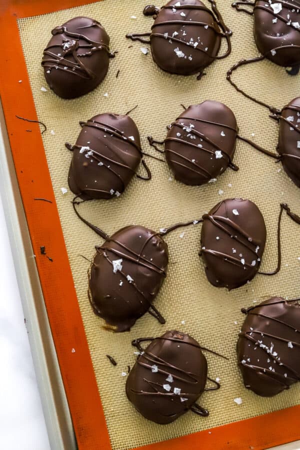 Chocolate covered peanut butter Easter eggs drizzled with chocolate and topped with sea salt on a lined baking sheet.