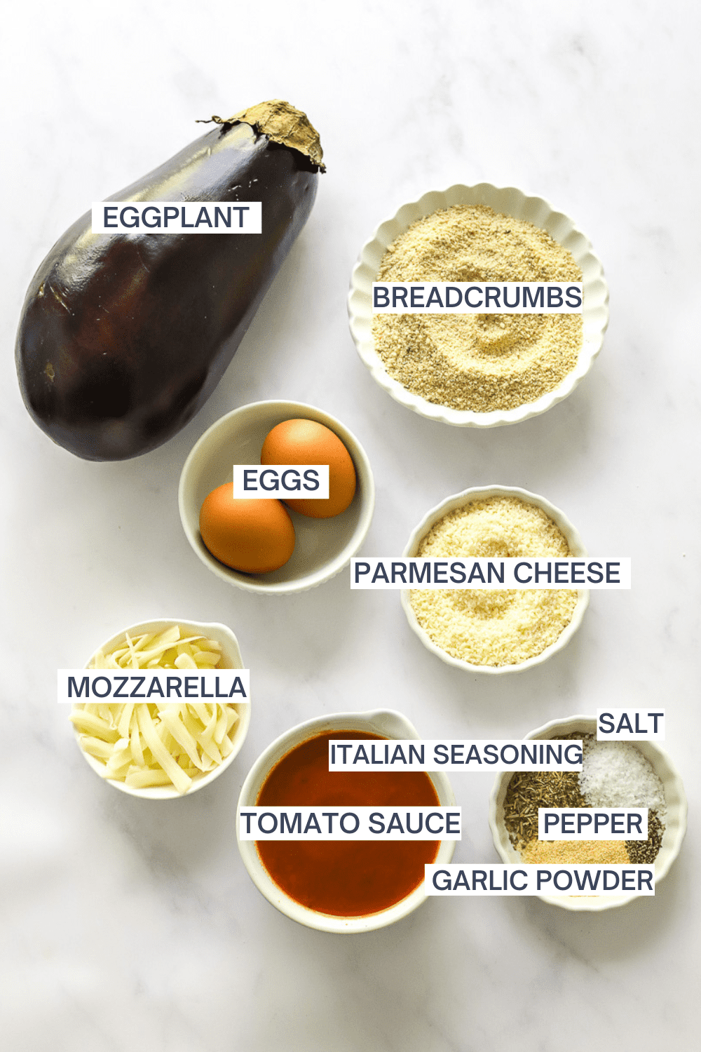 Ingredients for eggplant parmesan with labels over each ingredient. 