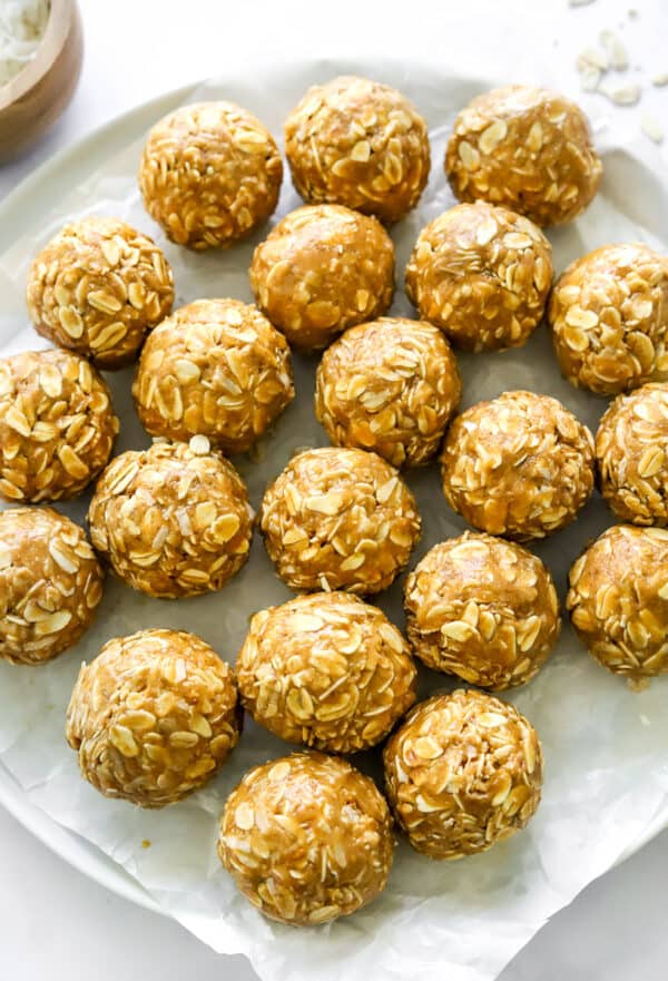 Plate topped with crinkled parchment paper full of creamy peanut butter balls.