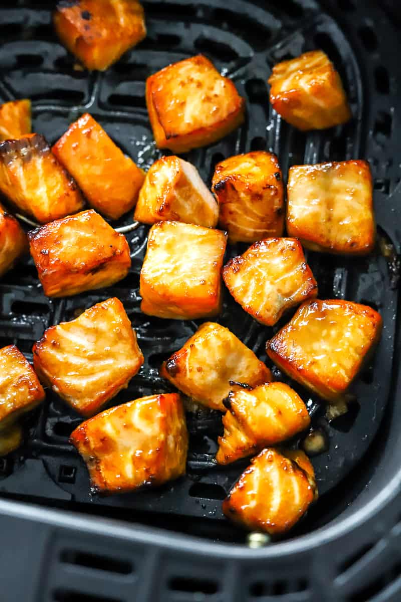 Cubed, golden cooked bites of salmon in an ir fryer basket. 