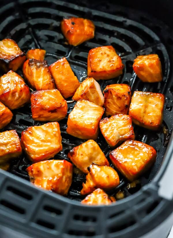 Cubes of golden cooked salmon in an air fryer.
