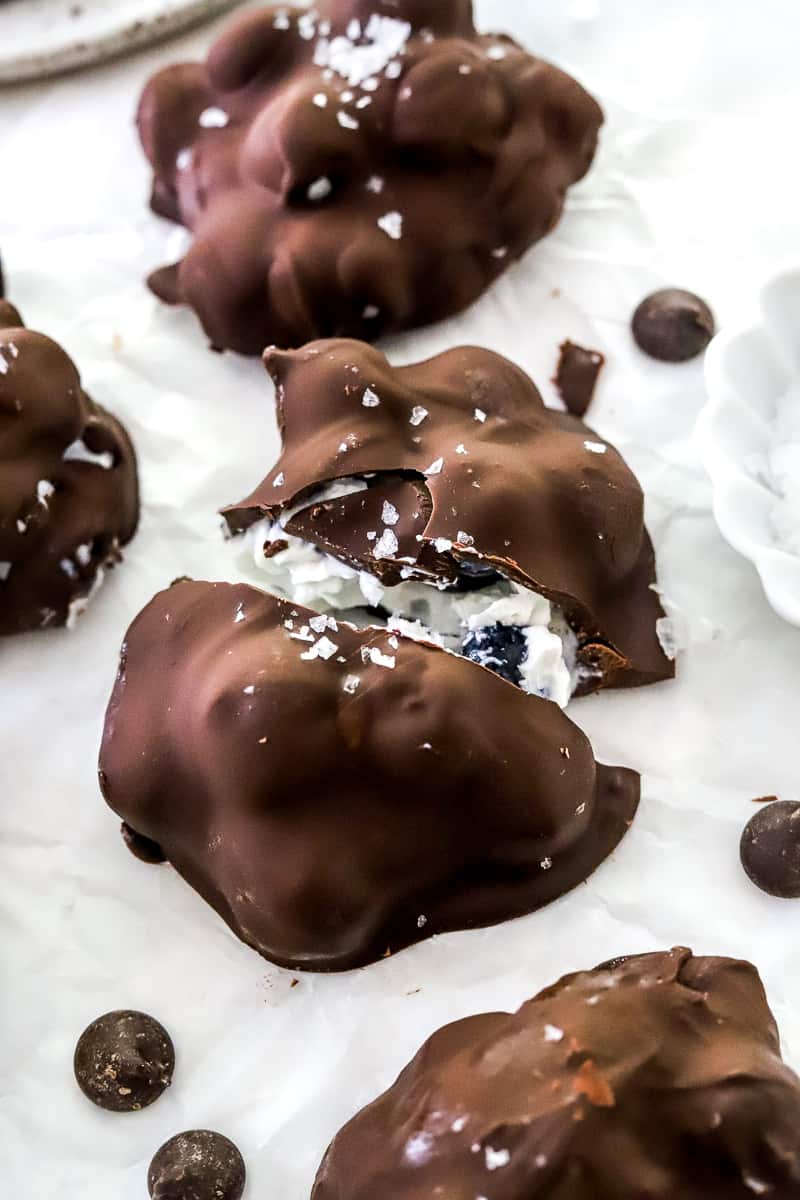 Chocolate covered berry yogurt cluster cut open on white parchment paper with more behind it