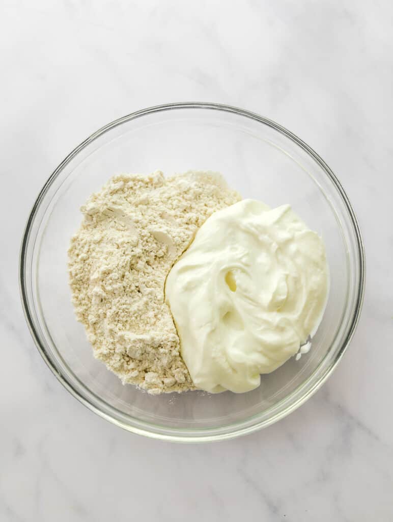 Greek yogurt and flour in a glass micing bowl.