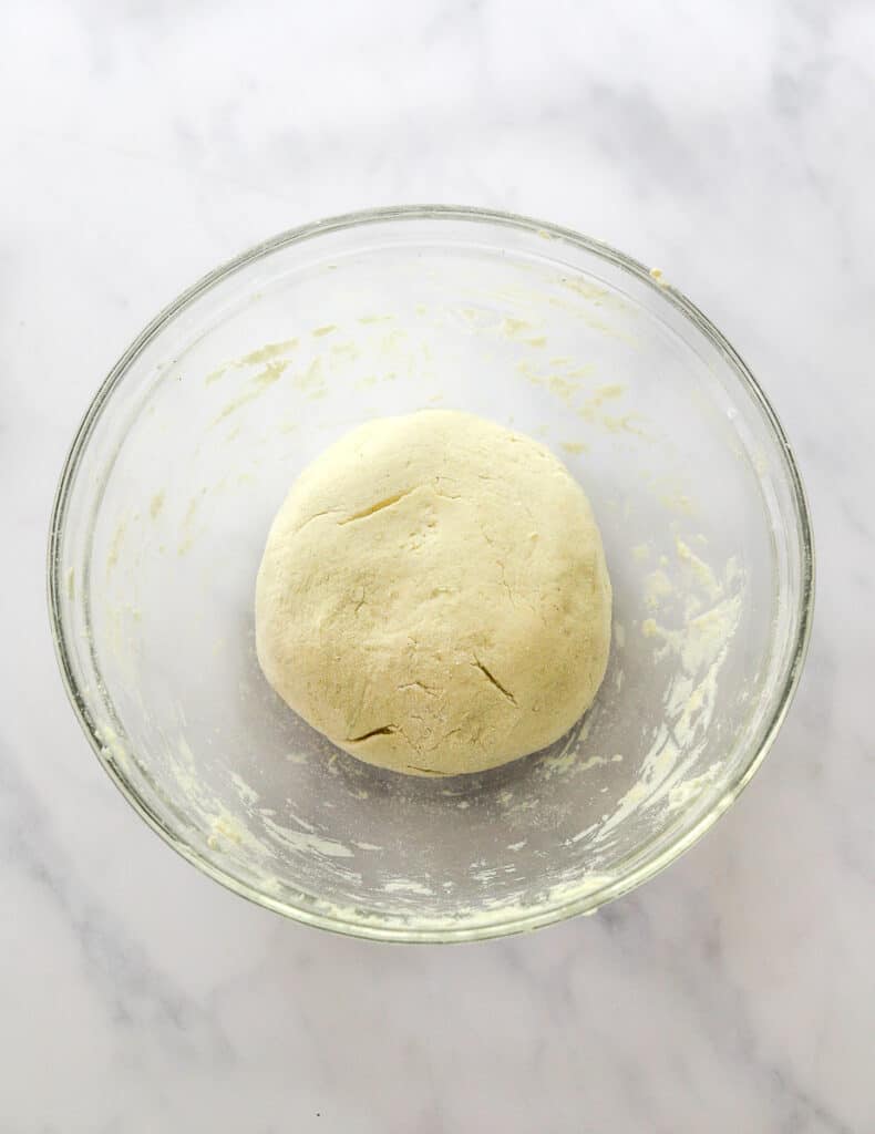 A round ball of dough in a glass bowl.