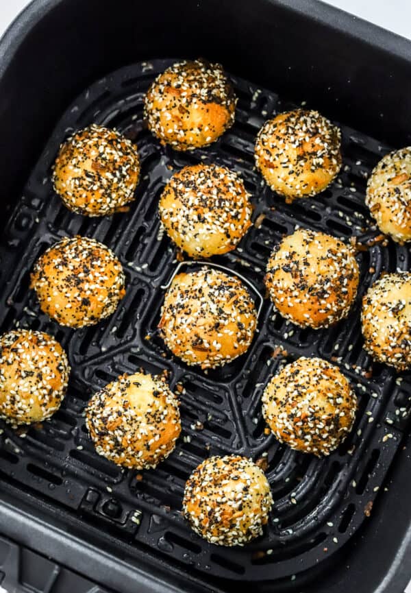 Cooked mini bagels with everything bagel seasoning on them in an air fryer basket.