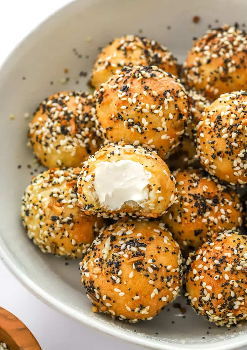 Everything bagel bites in a bowl with cream cheese spread on one of them.
