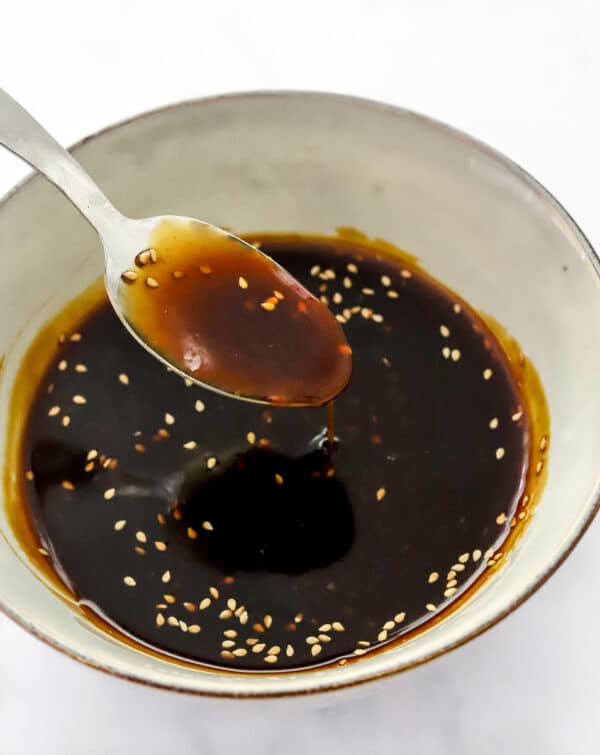 Gluten-free teriyaki sauce in a bowl with a spoon lifting some of the sauce out of the bowl.