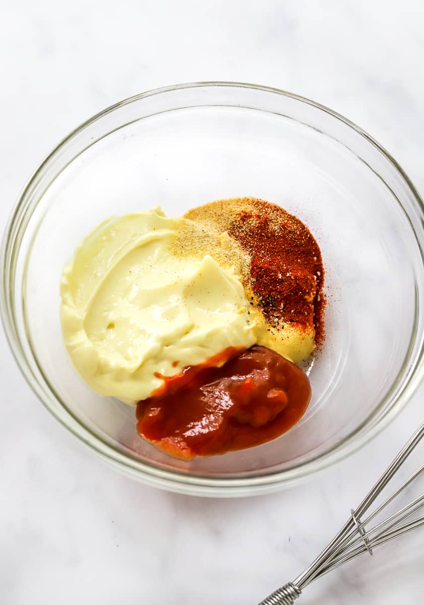 Mayo, ketchup, mustard, and spices ina round glass bowl.