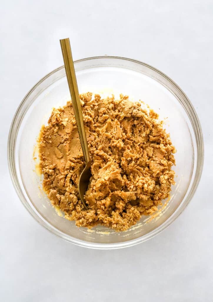 Mixed peanut butter, with almond flour and protein powder in a glass bowl with a spoon in the bowl.