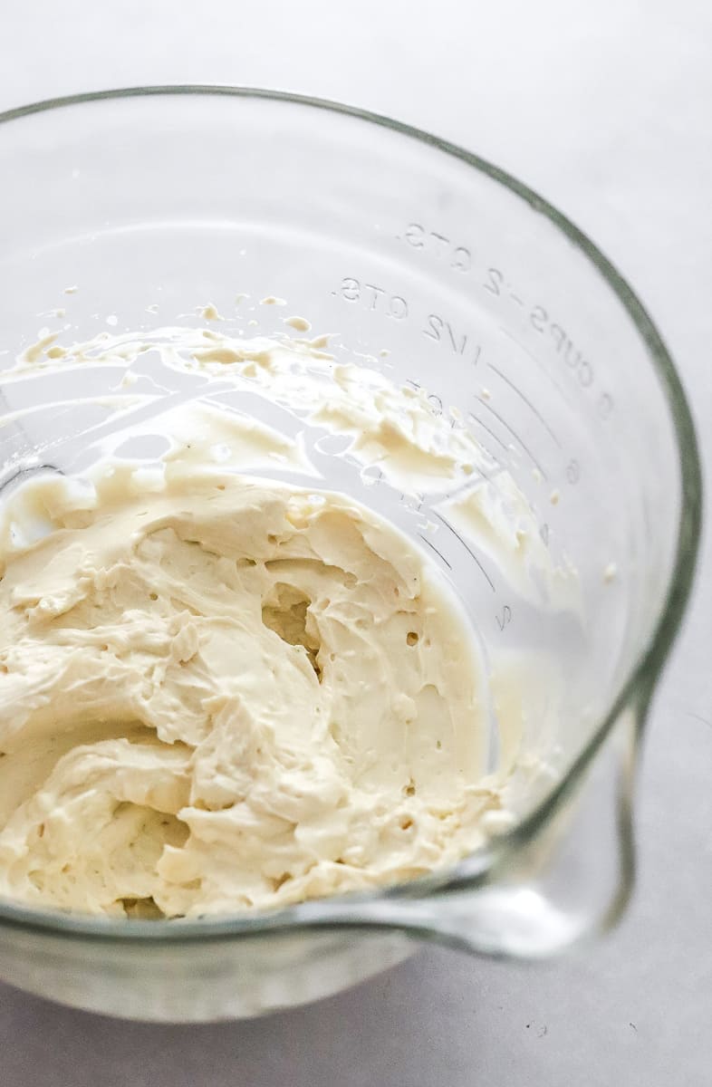 Cream cheese frosting mixed in a glass bowl.