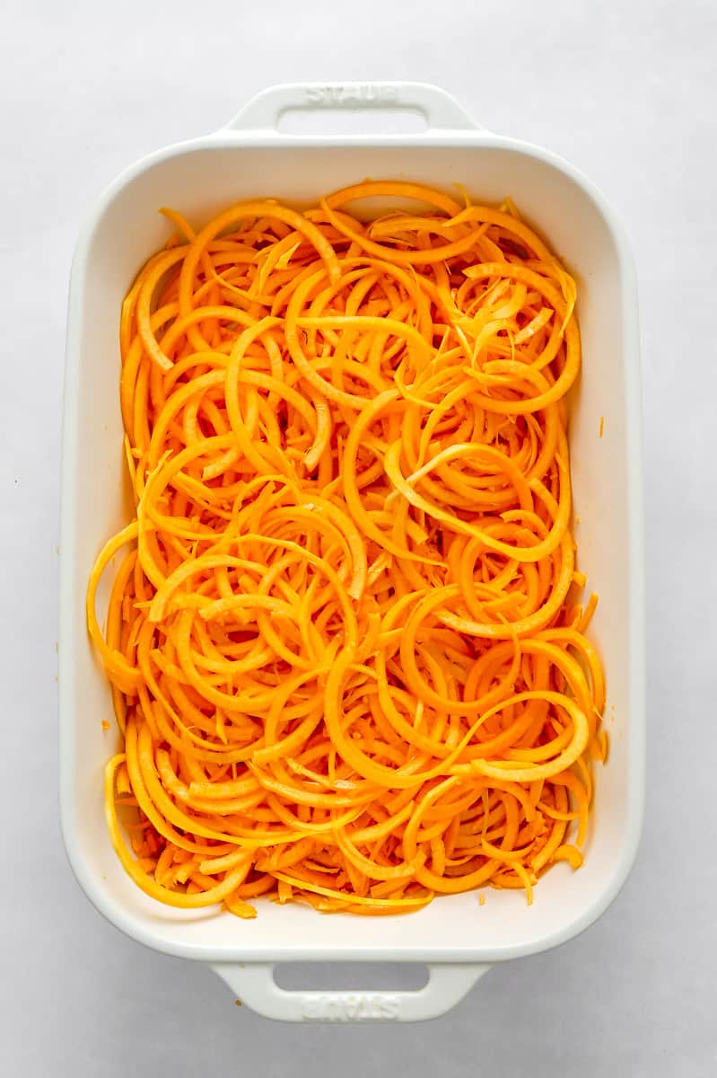 White baking dish filled with spiralled squash noodles. 