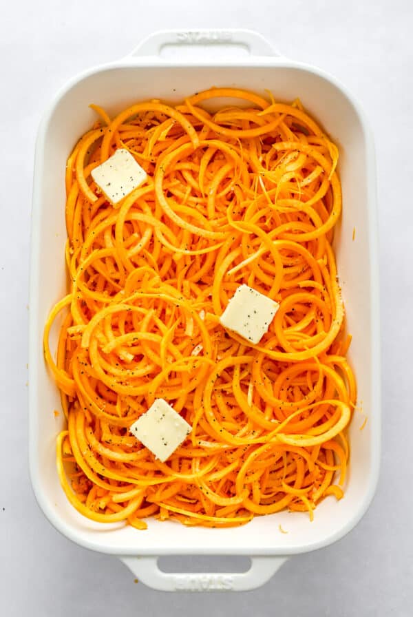 White 9/13 baking pan with butternut squash noodles in it topped with a few pats of butter.