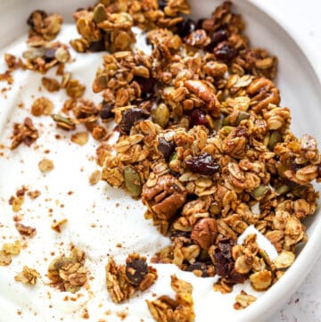 Round bowl filled with yogurt and topped with gluten free granola.