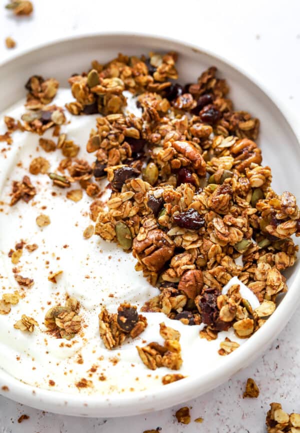 Round bowl filled with yogurt and topped with gluten free granola.
