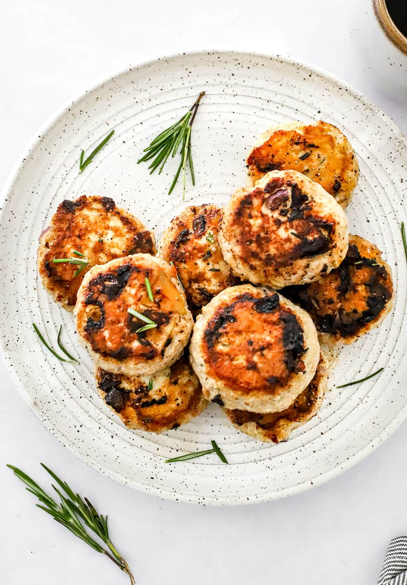Plate of cooked chicken mini patties with rosemary sprigs around them.