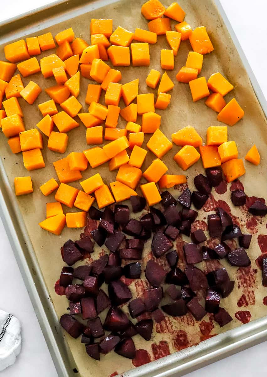 Roasted cubes of squash and beets on a baking sheet topped with brown paper.