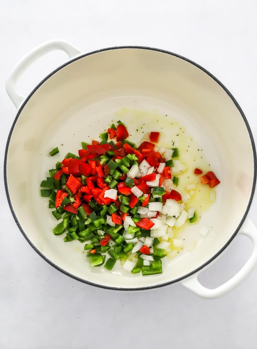 White pot with diced peppers and onions in it. 