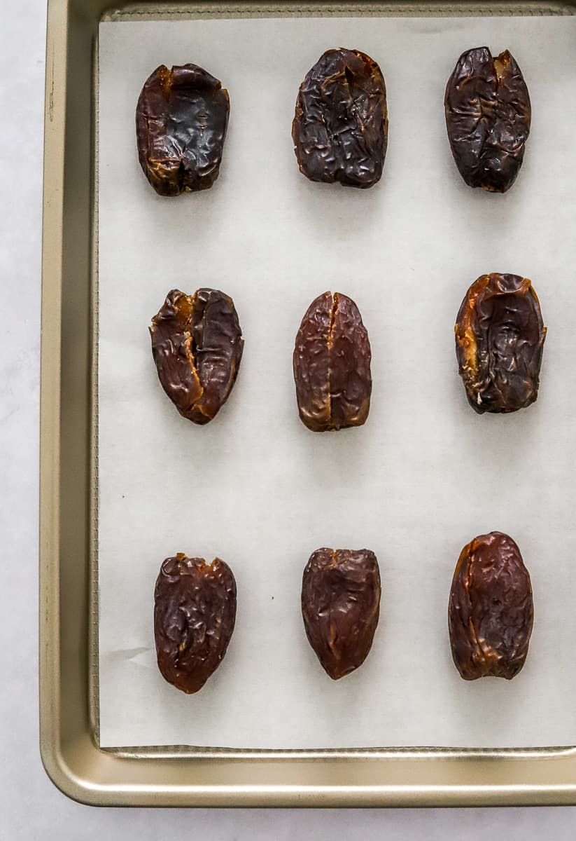 Dates on a lined baking sheet in rows.