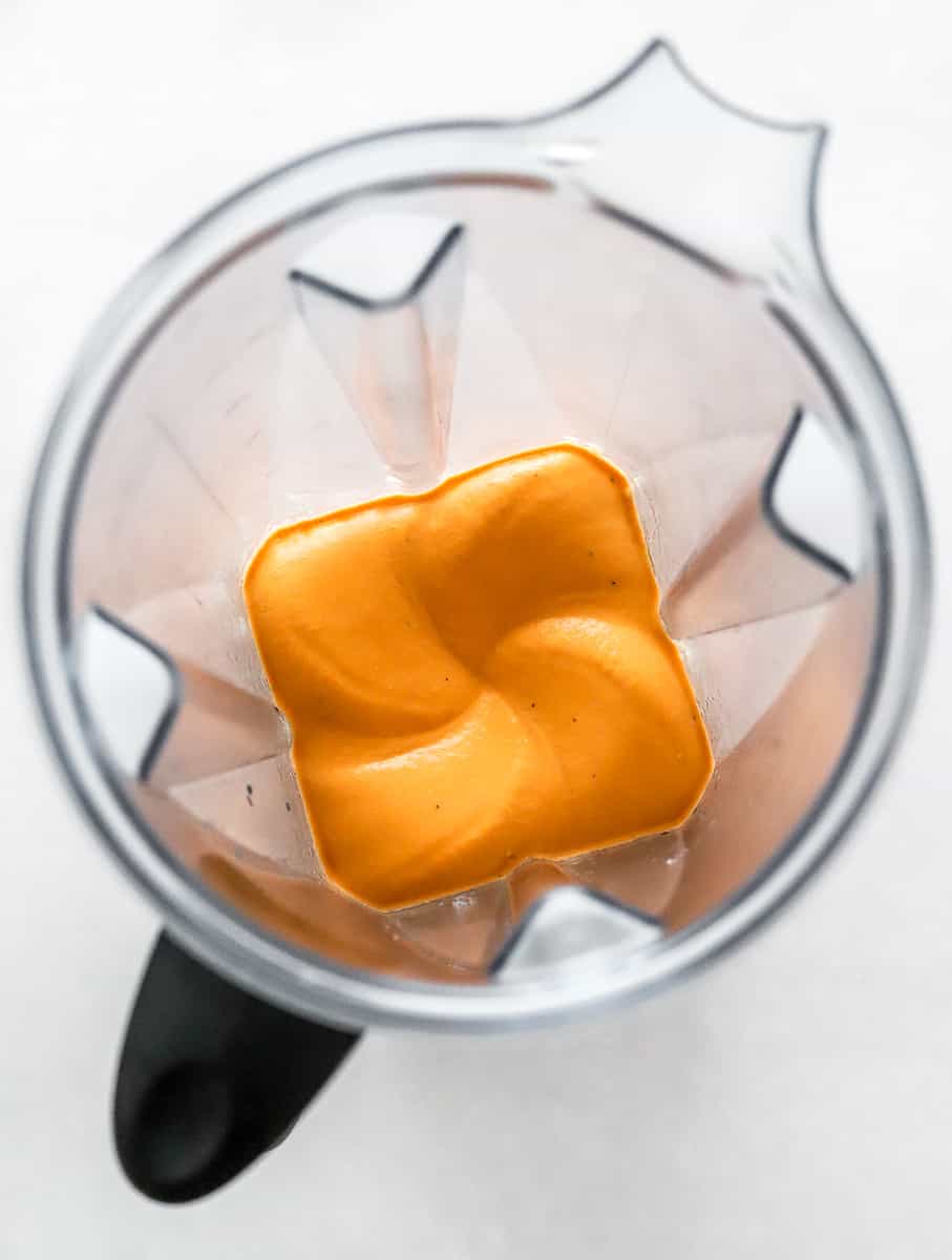 Blended orange hummus in a blender pitcher. 