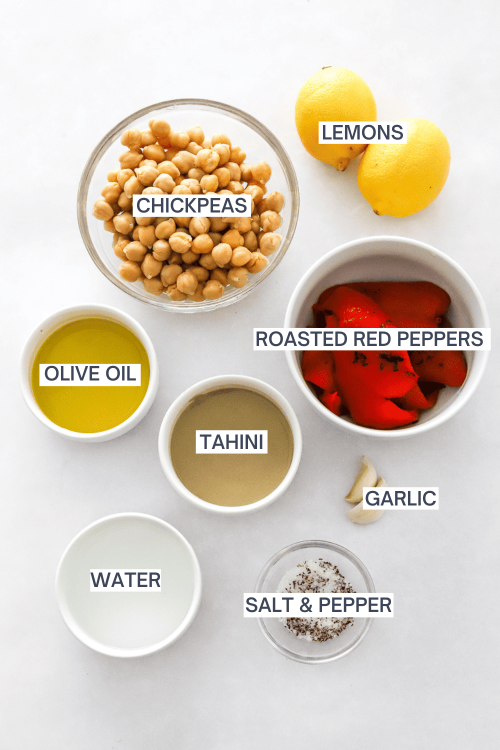 Ingredients for red pepper hummus in bowls with labels over each ingredient. 