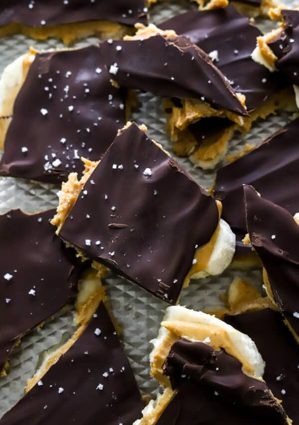 Frozen banana peanut butter chocolate bark pieces in a pile on a baking sheet.